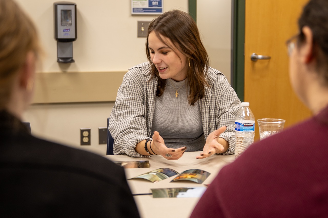 Person talking with printed photos on table